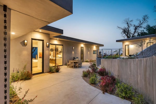 Infinity pool overlooking rolling hills and valleys, with patio seating and lounge chairs on manicured lawn